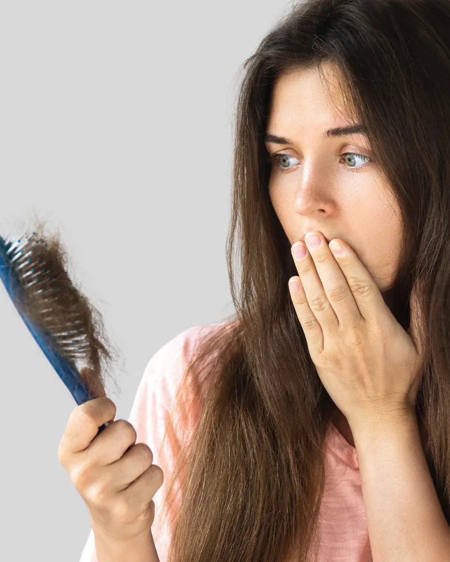 Eine Frau betrachtet Haare in ihrer Bürste